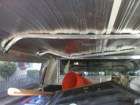 1978 Ford Bronco - View from inside a truck cap, showing insulation and various items stored in the bed.