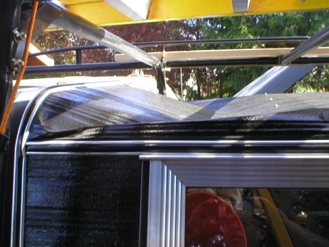 1978 Ford Bronco - A close-up view of a vehicle's side and roof rack, partially covered by a tarp.