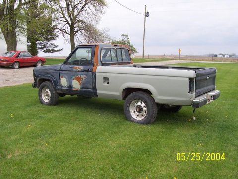 1988 Ford Ranger - A Ford Ranger pickup truck with mismatched paint and visible rust sits on a grassy lawn next to a red car.