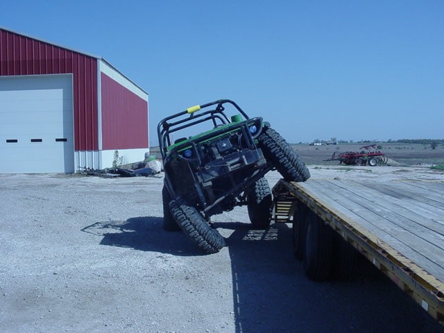 Green off-road vehicle tilted on a flatbed trailer