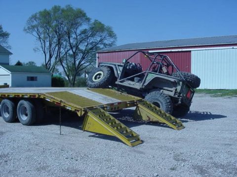 1992 Ford Bronco - A heavily modified off-road vehicle is positioned on the ramps of a flatbed trailer.