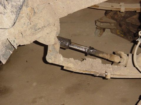 1992 Ford Bronco - Undercarriage view of a heavily corroded suspension component, possibly from an older off-road vehicle.