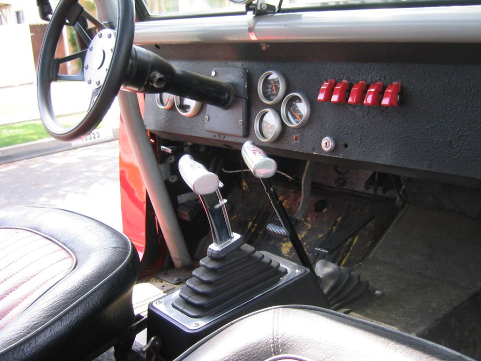 Early Ford Bronco interior with aftermarket gauges, red toggle switches and ratchet shifter