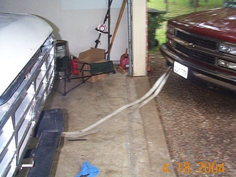 1986 Ford Bronco - Two trucks are parked in a garage, connected by clear hoses.