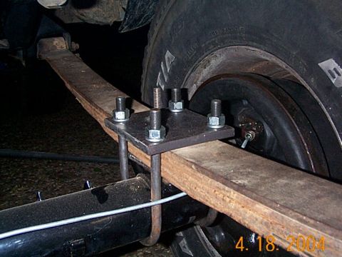 1986 Ford Bronco - Close-up view of a leaf spring with a U-bolt and plate modification, likely for suspension work.