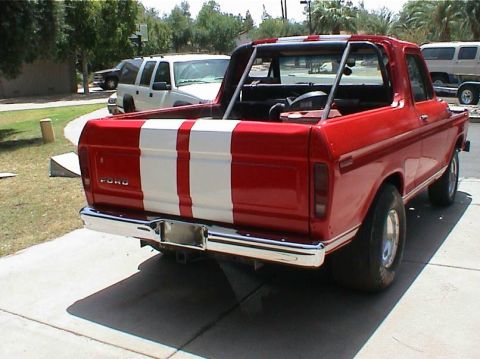 1979 Ford Bronco - Rear view of a red 1978 Ford Bronco with white racing stripes and a roll bar, parked on a concrete driveway.