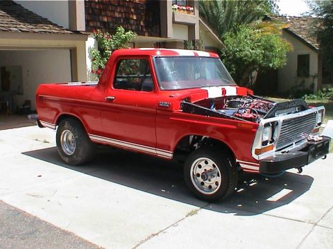 1979 Ford Bronco - This red 1979 Ford Bronco features white racing stripes and its hood is open, revealing the engine.