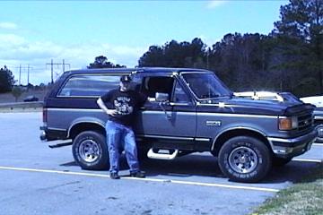 1989 Ford Bronco - A man poses with his two-tone Ford Bronco parked in a lot.