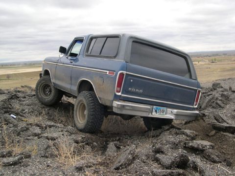 1978 Ford Bronco - A blue 1978 Ford Bronco navigates a rocky incline under an overcast sky.