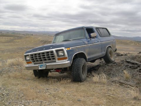 1978 Ford Bronco - This blue 1978 Ford Bronco is captured in a three-quarter front view as it navigates a rocky, uneven landscape.