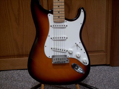 1986 Ford Bronco - A sunburst electric guitar is displayed against a wooden background.