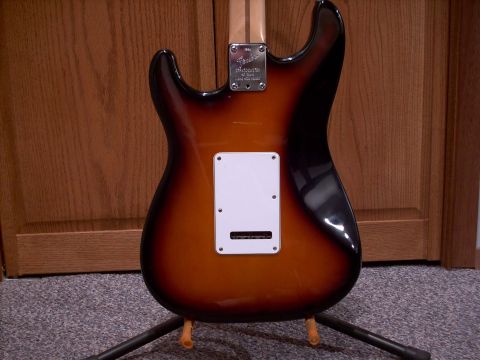 1986 Ford Bronco - Back view of a sunburst electric guitar on a stand, with wooden doors in the background.