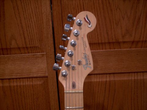 1986 Ford Bronco - Close-up of a Fender Stratocaster guitar headstock, showing tuning pegs and the Fender logo.