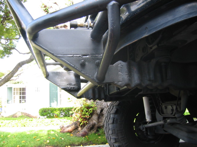 Black custom off-road bumper and suspension parts on a vehicle, with a tire visible