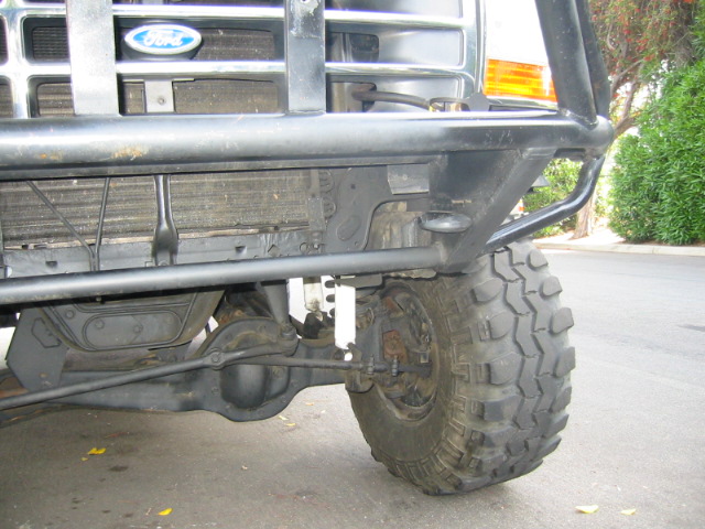 Ford truck front corner with black tube bumper, exposed radiator and knobby tire