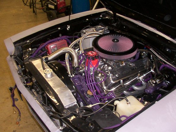 Engine bay with installed V8, red K&N-style air filter, purple plug wires and chrome valve covers