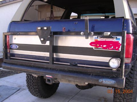 1994 Ford Bronco - The rear of a blue SUV is shown, a spare tire carrier, a California license plate, and a custom bumper.