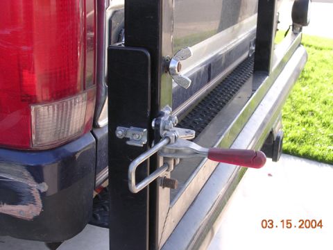 1994 Ford Bronco - Detail of a latch mechanism on a gate attached to the rear of a red vehicle.