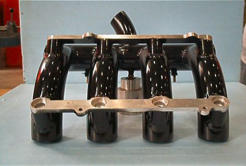 1985 Ford LTD Crown Victoria - A black intake manifold with a silver fuel rail is shown, likely a performance part for an engine.