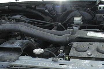 1989 Ford Bronco - Engine bay of a 1989 Ford Bronco, showing hoses and the brake master cylinder.