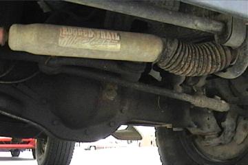 1989 Ford Bronco - Close-up view of the underbody of a vehicle, showing suspension components and a shock absorber.