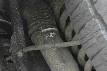 1989 Ford Bronco - Detail of a vehicle's suspension system, including a shock absorber and tire tread.