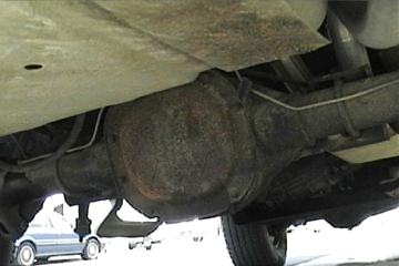 1989 Ford Bronco - Underside view of a vehicle's rear differential and suspension. Another car is partially visible in the background.