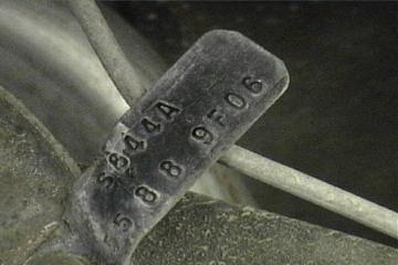 1989 Ford Bronco - Close-up of a part identification tag with stamped numbers and a website logo.