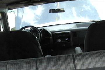 1989 Ford Bronco - View from the back seat of a truck, showing the dashboard and steering wheel. The hood is open.