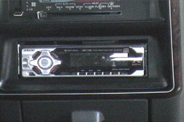 1989 Ford Bronco - Close-up of a car stereo unit, the SuperMotors website address at the bottom.