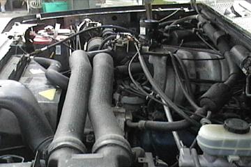 1989 Ford Bronco - Close-up view of a vehicle's engine compartment, showing various components and hoses.