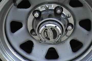 1989 Ford Bronco - A close-up view of a vehicle's wheel hubcap, the SuperMotors website logo at the bottom.