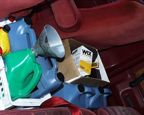 1988 Ford C-350 (Centurion Conversions) - The interior of a vehicle is filled with various oil containers and a box of Wix filters, suggesting a storage or transport situation.