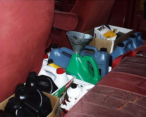 1988 Ford C-350 (Centurion Conversions) - Vehicle interior packed with oil containers, a funnel, and Wix filters, obscuring the view of the seats.