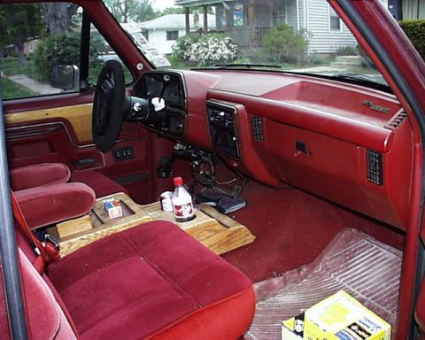 1988 Ford C-350 (Centurion Conversions) - The interior of a vehicle features red upholstery, wood accents on the door panels and center console, and a red dashboard.