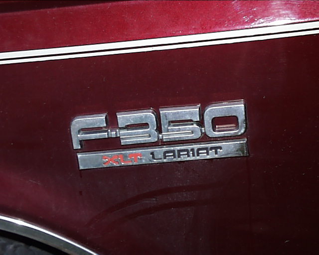 Chrome F-350 XLT Lariat emblem on a maroon truck body panel