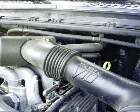 2003 Ford Excursion - The V10 engine air intake tube is visible in this close-up shot of engine components.