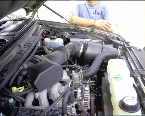 2003 Ford Excursion - The engine bay of a 2003 Ford Excursion is shown, with a person leaning over the side.