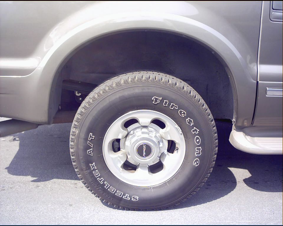 Front wheel of tan SUV with Firestone Steeltex A/T tire and silver alloy wheel
