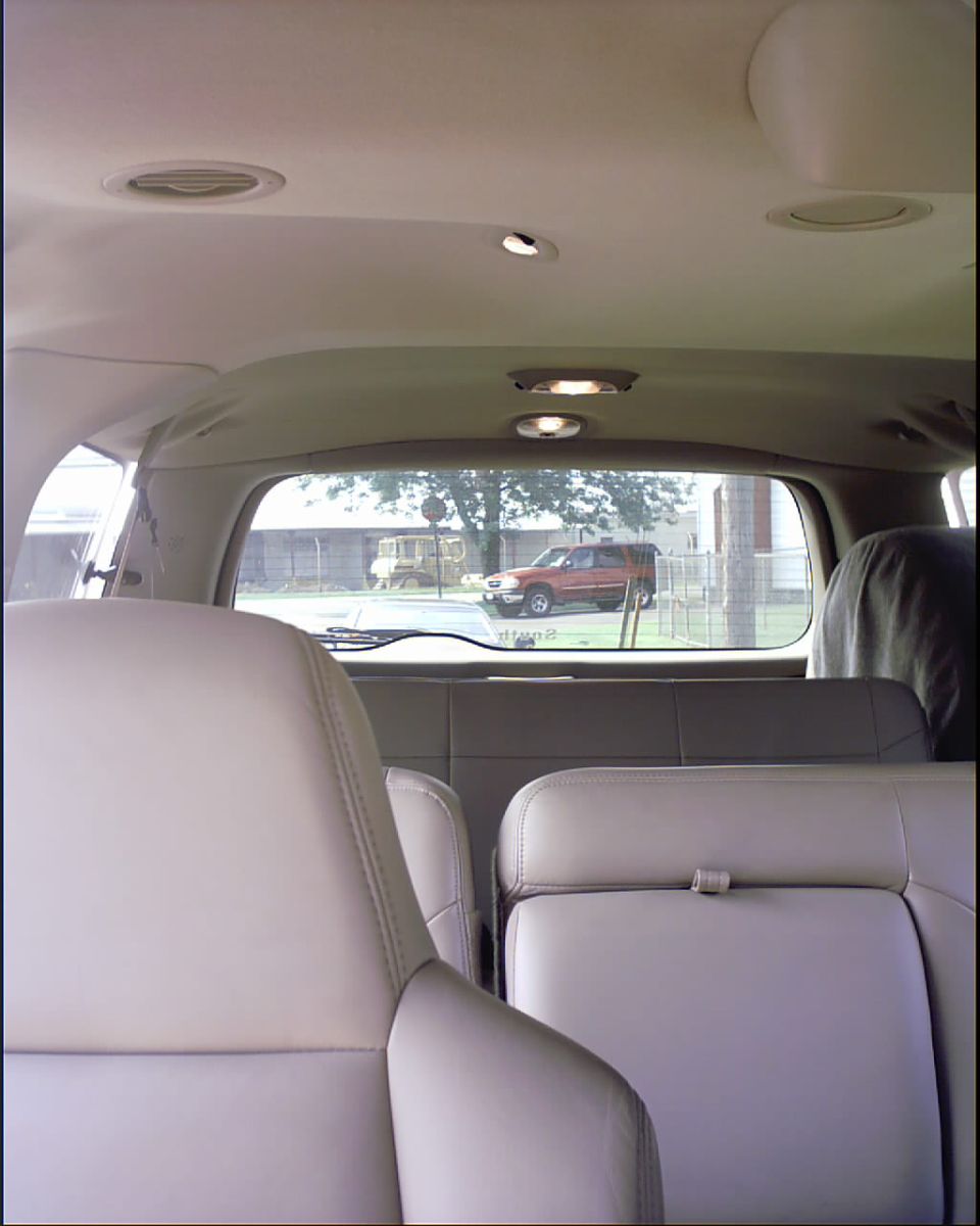 Tan leather SUV interior looking toward rear window with red pickup visible outside