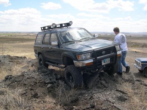 1978 Ford Bronco - SUV with roof rack and brush guard navigating rough terrain, another vehicle visible to the right.