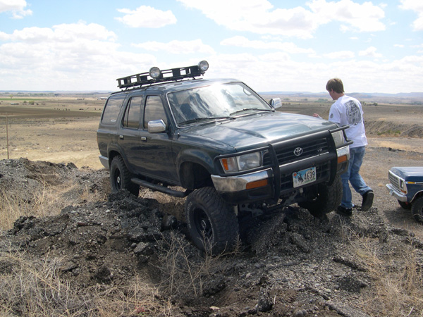 Dark green SUV with roof rack and brush guard on rough terrain; license plate reads W 4639