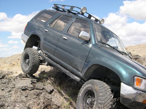 1978 Ford Bronco - This green SUV is equipped for off-roading with a roof rack and large tires, navigating a challenging rocky path.