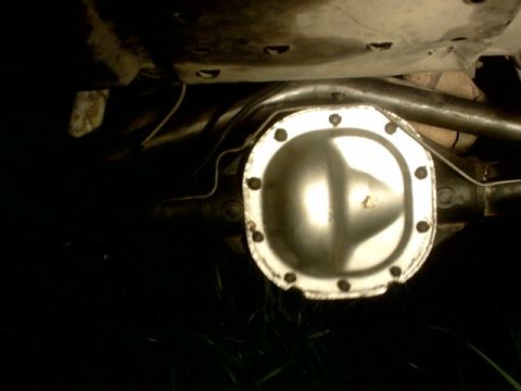 1995 Ford Bronco - Undercarriage view of a vehicle's rear differential cover, showing bolted connections and surrounding components.