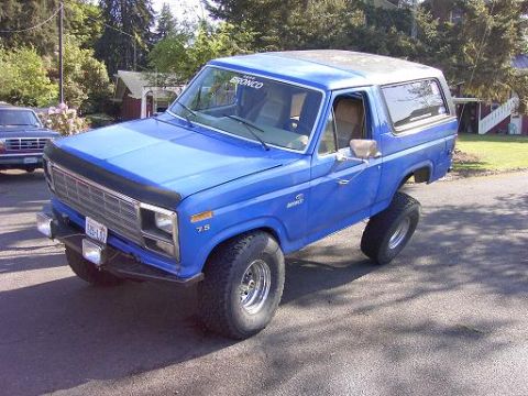 1980 Ford Bronco - This blue 1980 Ford Bronco is parked outside with a lifted suspension and large tires.