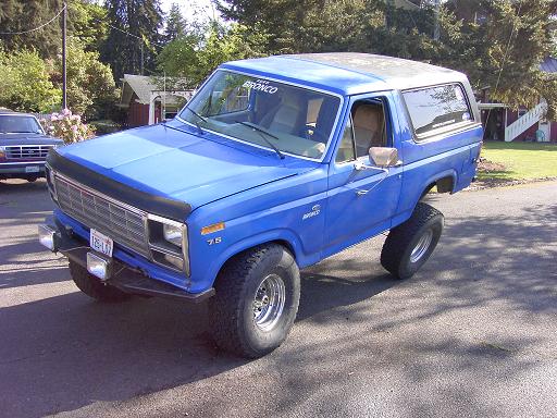 Blue 1980s Ford Bronco front three-quarter with hood deflector and BRONCO windshield banner