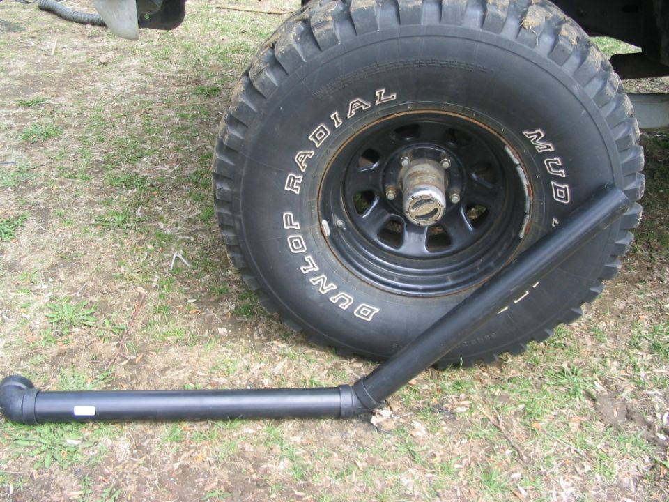 Spare tire on black steel wheel with Dunlop Radial Mud tire and steering link on grass