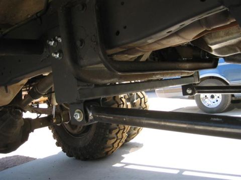 1994 Ford Bronco - Undercarriage view of a vehicle's suspension and tire, with another vehicle in the background.