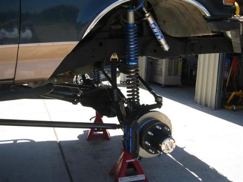 1994 Ford Bronco - Close-up of a vehicle's front suspension system, upgraded King shocks and a prominent brake rotor, supported by jack stands.