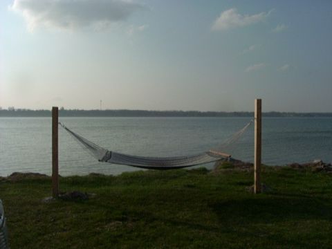 1992 Ford Bronco - A hammock hangs over a grassy area next to a large body of water under a cloudy sky.
